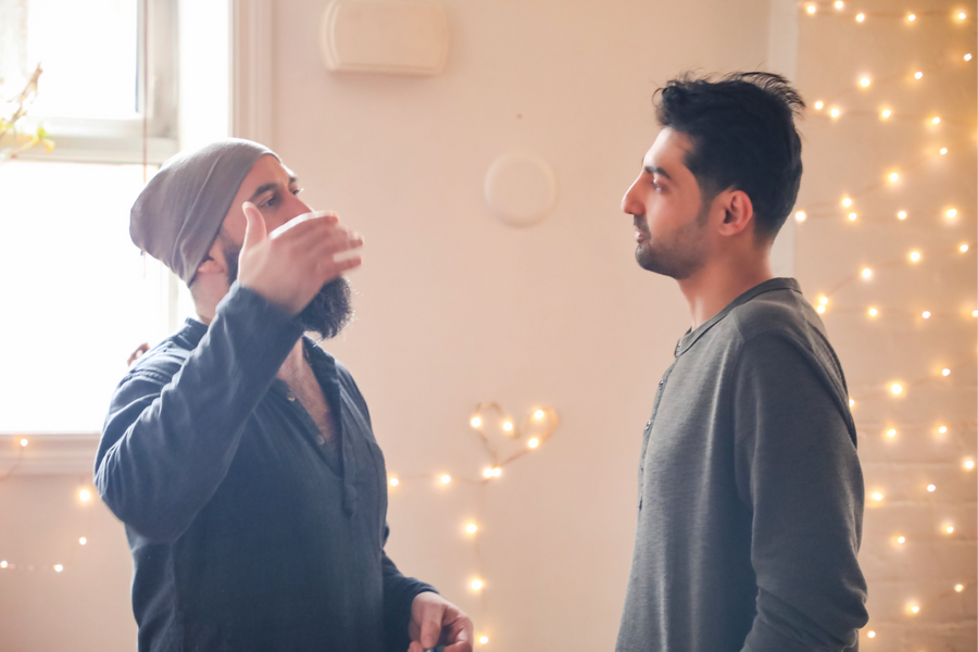 Two men standing in a room, discussing consciousness and yoga. 